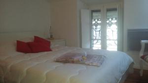 a white bed with red pillows and a window at Appartement FARIO in Ax-les-Thermes