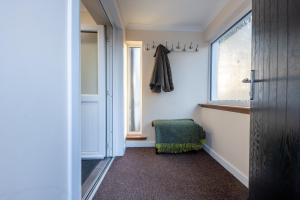 a hallway with a green chair and a window at Silverbridge Lodge in Garve