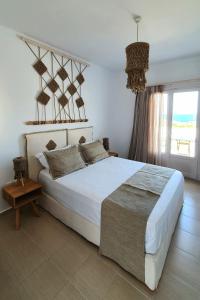 Un dormitorio con una gran cama blanca y una ventana en Sarakiniko Rooms en Adamas