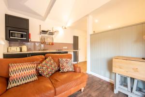 a living room with a brown couch and a kitchen at Little Wyvis Lodge in Garve