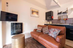 a living room with a brown leather couch and a kitchen at Little Wyvis Lodge in Garve