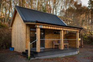 a small wooden cabin with a deck in the woods at Little Wyvis Lodge in Garve