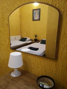 a mirror on a wall with two beds and a lamp at Gościniec Głuchołazy Zdrój in Głuchołazy