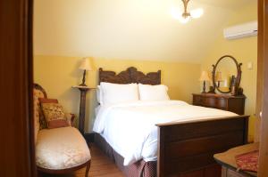 1 dormitorio con 1 cama blanca grande y 1 silla en Magnetic Hill Winery, en Moncton