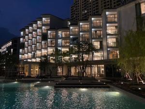 a building with a pool in front of it at night at The Quarter Chaophraya by UHG in Bangkok