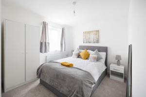 a white bedroom with a large bed with yellow pillows at Fortified Three Bedroom Home Bristol 