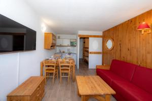 イゾラ 2000にあるRésidence Capfun Les Adretsのリビングルーム(赤いソファ付)、キッチン