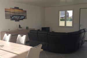 ein Wohnzimmer mit einem Sofa und einem Tisch in der Unterkunft Maison neuve proche de la mer in Créances