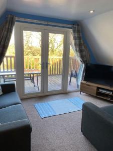 a living room with a couch and a sliding glass door at 3 Bedroom Lodge with hot tub on lovely quiet holiday park in Cornwall in Gunnislake