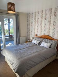 un grande letto in una camera da letto con finestra di 3 Bedroom Lodge with hot tub on lovely quiet holiday park in Cornwall a Gunnislake