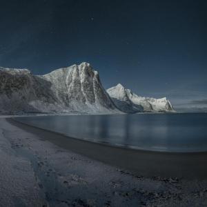 ein Strand in der Nacht mit schneebedeckten Bergen in der Unterkunft Skagi Senja hotel & lodge in Skaland