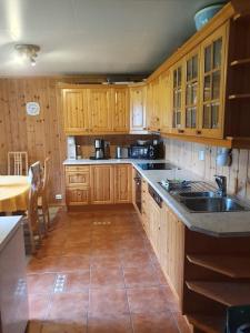 a kitchen with wooden cabinets and a sink and a table at Vingvågen hygge og ro in Hitra