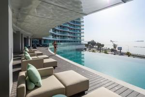 a man standing next to a swimming pool next to a building at Limassol Del Mar in Limassol
