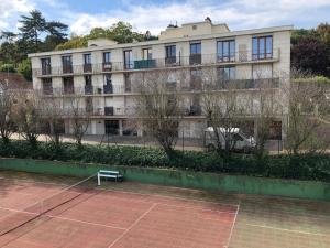 un campo da tennis di fronte a un edificio di Studio Villennes sur Seine près de la gare a Villennes-sur-Seine