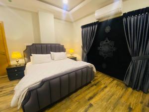 een slaapkamer met een groot bed met een zwart hoofdeinde bij Holidazzle Serviced Apartments Bahria Town in Rawalpindi