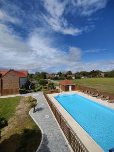 a swimming pool in a yard with chairs around it at Le Village du Phare in Gouville-sur-Mer