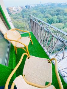 two chairs sitting on a balcony with green grass at Holidazzle Serviced Apartments Bahria Town in Rawalpindi