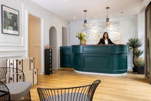 a woman is standing behind a green counter in a room at Nord Est Hotel in Paris