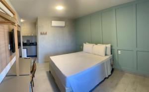 a bedroom with a large white bed and a kitchen at Liiv Mar - Natal Ponta Negra in Natal