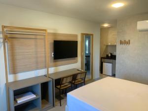 a room with a table and a tv and a kitchen at Liiv Mar - Natal Ponta Negra in Natal