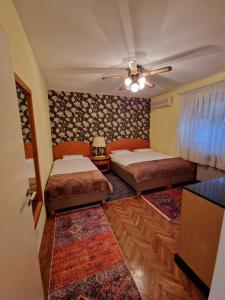 a bedroom with two beds and a ceiling fan at Avalon Apartments in Belgrade