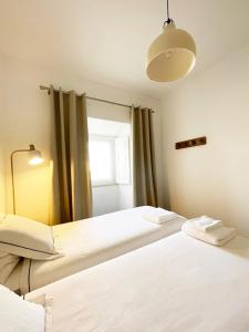 Duas camas num quarto com uma janela em Casa Sagres T2 - 3 minutos a pé Praia da Mareta em Sagres