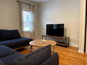 a living room with a couch and a table and a tv at Lovely Two Bedroom Condo in South Boston in Boston