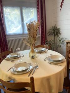 une table avec des assiettes et des verres et un vase avec des fleurs dans l'établissement Joli studio proche Valmorel, à Aigueblanche
