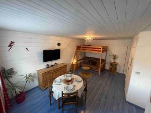 a room with a table with chairs and a television at Joli studio proche Valmorel in Aigueblanche