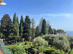 um grupo de árvores e arbustos com o oceano ao fundo em Papiro House em Taormina