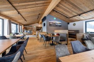 restauracja z drewnianymi sufitami, stołami i krzesłami w obiekcie Aparthotel Fuxbau w mieście Flachau