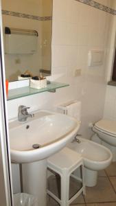 bagno bianco con lavandino e servizi igienici di Residenza Turistico Alberghiera Corallo a Castiglione della Pescaia