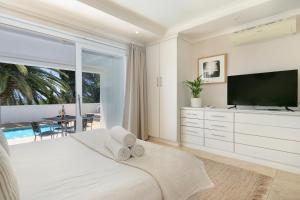 Dormitorio blanco con TV y cama en Ingleside Luxury apartment by Totalstay, en Ciudad del Cabo