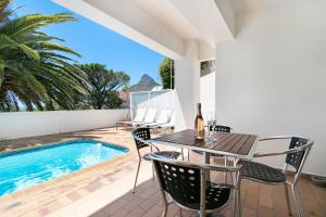 un patio con mesa y sillas junto a una piscina en Ingleside Luxury apartment by Totalstay, en Ciudad del Cabo