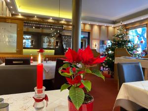 Un árbol de Navidad en un restaurante con flores rojas en una mesa en Parkhotel Traunstein, en Traunstein