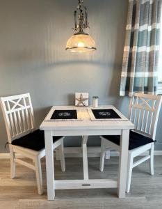 tavolo bianco da pranzo con due sedie e luce di Ferienwohnung Meeresblick Cordy a Sankt Peter-Ording
