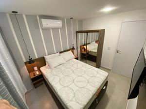 a small bedroom with a bed and a mirror at Flat Premium No Centro in Porto De Galinhas