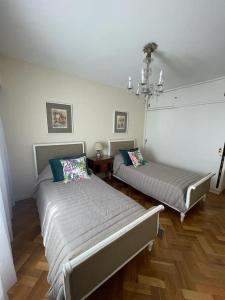 1 dormitorio con 2 camas y lámpara de araña en Departamento de Categoría Av. España en Mendoza