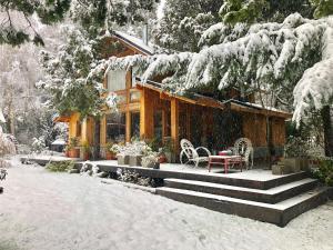 a house covered in snow with a table and chairs at Hogar de Montaña in Villa La Angostura