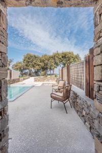 a chair sitting next to a stone wall next to a pool at Paros Comfy Suites in Naousa