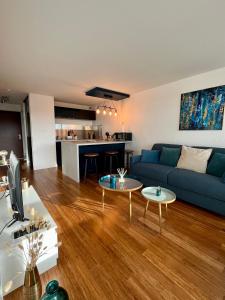 a living room with a blue couch and two tables at Appartement cosy avec vue mer in Stella-Plage