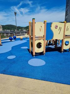a playground with a blue carpet and wooden play equipment at Apartamento San Marcos by SanSe Holidays in Donostia-San Sebastián