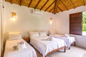 a room with two beds and a window at POUSADA CARMELITHA in Trancoso