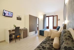 Habitación de hotel con sofá, cama y escritorio. en Le Falesie di Castelluzzo en Castelluzzo