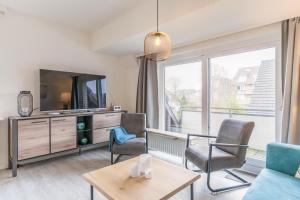 a living room with a tv and two chairs and a table at "Haus Deichlodge" deichlodge lodge fünf in Büsum