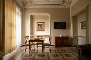 een eetkamer met een tafel en stoelen en een televisie bij CORVETTO rooms in Genua