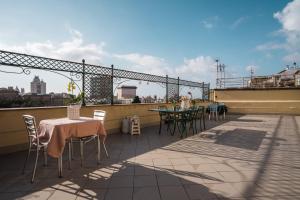 een patio met tafels en stoelen op een dak bij CORVETTO rooms in Genua