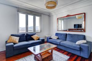 una sala de estar con 2 sofás azules y una mesa. en Apartamento Ulia by SanSe Holidays, en San Sebastián