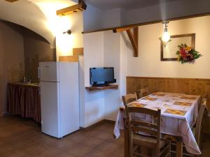a kitchen with a table and a white refrigerator at AL BORGO ANTICO residenza in Pinzolo