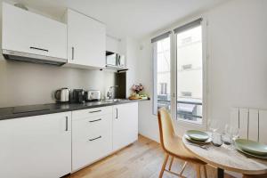Stunning apartment 4P1BR في باريس: مطبخ مع دواليب بيضاء وطاولة مع كراسي